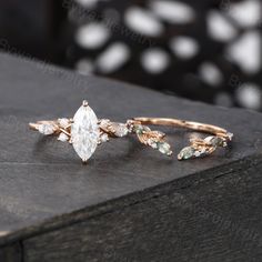 three different types of wedding rings sitting on top of a wooden table with white and green stones