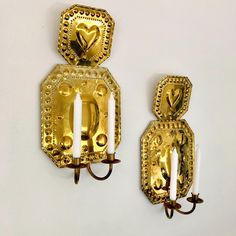 two gold wall sconces with candles on them