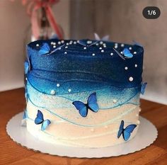 there is a blue and white cake with butterflies on it