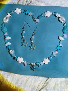 Capture the essence of beachy shores with our delightful beach-themed jewelry set! Adorn yourself with shimmering seashells and sparkling sea glass in the form of earrings, a necklace, and a stylish glasses chain. Perfect for adding a touch of seaside charm to any outfit, these pieces are your ticket to coastal bliss wherever you go <3 Beaded Shell-shaped Jewelry For The Beach, Ocean-inspired Jewelry With Round Beads For Beach Season, Shell-shaped Beaded Jewelry For Beach Season, Ocean-inspired Round Beads Jewelry For Beach Season, Ocean-inspired Beaded Jewelry, Beach Jewelry With Beaded Ocean Color, Ocean Blue Beaded Jewelry For Beach, Ocean-colored Beaded Jewelry For Beach, Beaded Sea Glass Jewelry For Beach