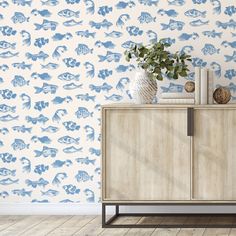 a blue and white wallpaper with fish on it in a room next to a wooden cabinet