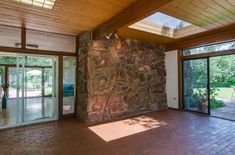 an empty living room with large windows and stone wall in the center, surrounded by brick flooring