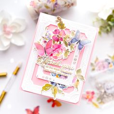 a close up of a card with flowers and butterflies on the front, surrounded by other crafting supplies