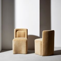 two chairs sitting next to each other in front of a white wall with shadows on it