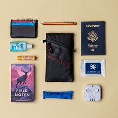 the contents of a travel bag laid out neatly on a table with passport, earbuds, eyeglasses and other items