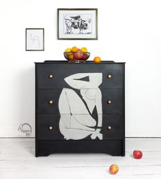 a black and white dresser with fruit on top of it next to an apple bowl