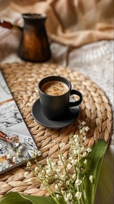 a cup of coffee sitting on top of a wicker tray next to a book