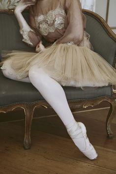 a woman sitting on top of a green chair wearing a dress and white socks with her legs crossed