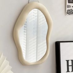 an oval shaped mirror hanging on the wall next to a black and white framed photograph