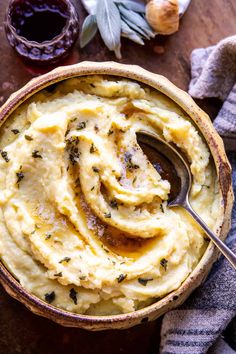 mashed potatoes in a bowl with a spoon and garlic on the table next to it