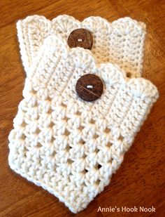 two white crocheted bags with brown buttons on them sitting on a wooden table