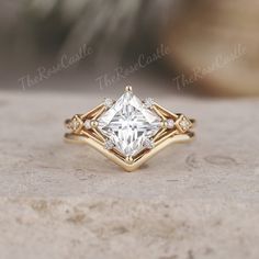 a gold ring with a princess cut diamond in the center and three small diamonds on each side