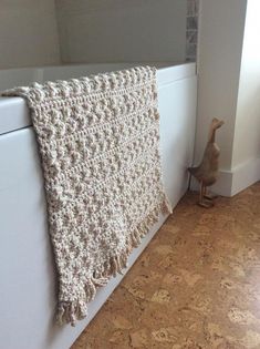 a cat sitting on the floor next to a blanket