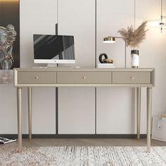 a desk with a computer on it in front of a white wall and wooden floor