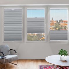 a living room with three windows that have blinds on them, and a chair in front of the window