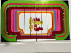 the price is right sign in front of a white wall with red, green, yellow and blue stripes