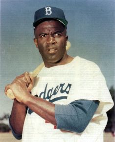 a baseball player is posing for a photo with his bat in one hand and wearing a hat on the other