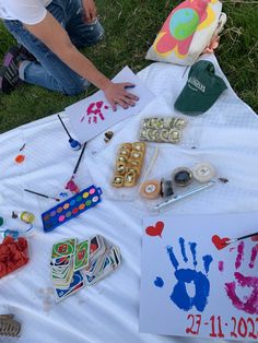 a man sitting on top of a white blanket covered in art and craft supplies next to a child's handprint