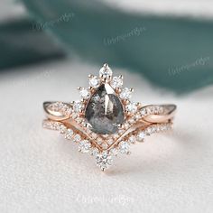 an engagement ring with a pear shaped gray diamond surrounded by small white and pink diamonds