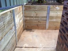 a wooden bench sitting in the middle of a yard next to a brick wall and planter