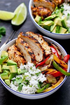 two bowls filled with chicken, rice and veggies next to lime wedges