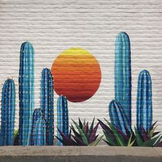 a mural painted on the side of a building with cactus and sun in the background