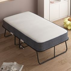 a mattress sitting on top of a bed frame in a room next to a book shelf