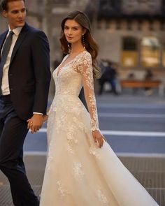 a man in a suit and tie walking next to a woman in a wedding dress