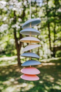 a wind chime hanging in the middle of a park with trees in the background