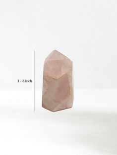 a large pink rock sitting on top of a white table next to a measuring ruler