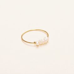 A dainty and minimal ring that is made to stand the test of time. This is a newer member of our pearl collection. With the freshwater rice pearls, this piece is for today, tomorrow, and always. - Materials: 18K gold plated titanium and freshwater pearls - Measurements: pearls are approximately 2mm in diameter - Sizes: US3- US9 - Note: the shape of the pearls may be a bit different from each other as they all grew naturally - The product is tarnish-resistant and hypoallergenic Minimalist Pearl White Ring With Pearl Drop, Dainty Hypoallergenic Pearl Ring For Everyday, Dainty Everyday Hypoallergenic Pearl Ring, Minimalist Pearl Stackable Jewelry, Minimalist Pearl White Pearl Ring, Adjustable Minimalist Pearl Ring, Minimalist Stackable Pearl Jewelry, Minimalist Pearl Rings With Pearl Charm, Minimalist Everyday Rings With Pearl Drop