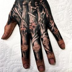 a person's hand covered in black and grey ink with an artistic design on it