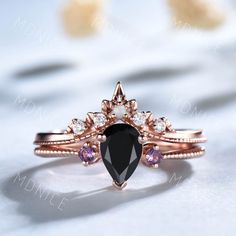 an engagement ring with a black diamond surrounded by pink and white stones on top of it