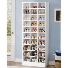 a white shoe rack filled with lots of shoes next to a blue wall in a room