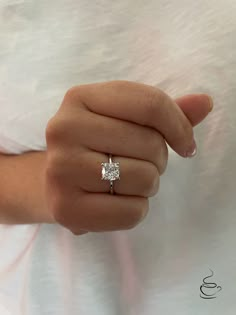 a woman's hand with a diamond ring on her finger, showing the center stone