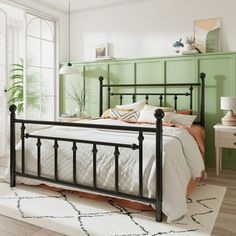 a bed room with a neatly made bed next to a green headboard and night stand