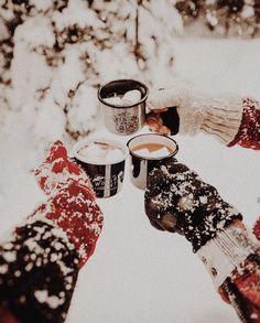 four people holding cups in the snow with their hands together and looking up into the sky