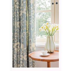 a vase filled with flowers sitting on top of a wooden table next to a window