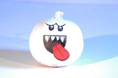 a white pumpkin with a red tongue sticking out of it's mouth on a blue surface