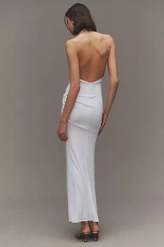 the back of a woman in a white dress with her hands on her hips, looking down