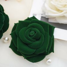 a close up of a green flower on a white table cloth with pearls around it