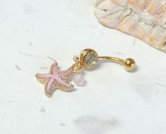 Starfish Belly Ring Show off your beautiful belly! Belly ring features a textured golden starfish charm with sparkly pink enamel accented with a hand wire wrapped pink agate bead. Belly button ring measures 1 3/4 inches long total length. Barbell is 14g gold plated surgical steel with a 10mm wearable bar length. For Belly Button Rings: https://www.etsy.com/shop/AllAboutClass?section_id=18474235&ref=shopsection_leftnav_1 For Industrial Barbells: https://www.etsy.com/shop/AllAboutClass?ref=l2- Starfish Belly Button Ring, Cute Belly Ring, Pink Starfish Jewelry For Gift, Pink Star Jewelry With Starfish Charm, Pink Starfish Charm Jewelry, Pink Star-shaped Jewelry With Starfish Charm, Summer Belly Rings, Cute Belly Button Piercing, Gold Belly Button Piercing