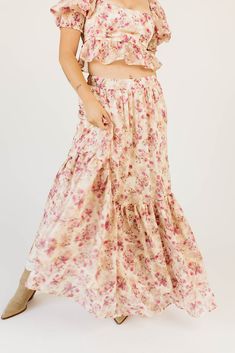 make everyone stop, stare, + have severe outfit envy with this iconic pink floral maxi skirt set. featuring a puff sleeve peplum cropped top + a matching flowy maxi skirt, it’s full of vintage vibes + versatility. you can wear the pieces together as a flirty formal ensemble, or separately to elevate any outfit. cream pink floral // square neckline, cropped, elastic cuffs, smocked back, elastic shoulders, tie back, maxi length, elastic back waist, ruffle skirt, lined skirt model is 5'8" + wearing Feminine Floral Print Maxi Skirt For Spring, Feminine Maxi Skirt For Spring, Feminine Spring Maxi Skirt For Garden Party, Feminine Flowy Maxi Skirt With Floral Print, Feminine Maxi Skirt, Flowy Pink Maxi Skirt For Spring, Pink Ruffled Skirt Maxi Dress For Spring, Flowy Feminine Maxi Skirt With Floral Print, Bohemian Pink Skirt For Garden Party