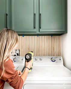 a woman using a dryer on top of a washer