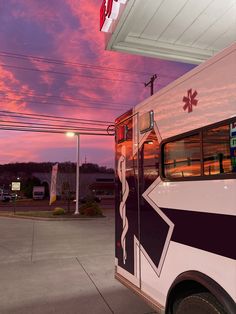 an ambulance parked in front of a gas station with the sun setting on it's horizon