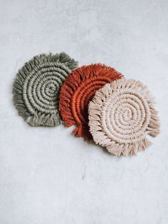 three different colored round rugs on a white surface