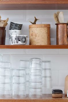 some cups are sitting on top of the shelves