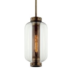 an antique brass and clear glass pendant light with a single bulb hanging from the ceiling