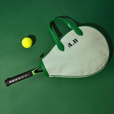 a tennis racquet, ball and bag sitting on a green surface with the name ab written on it