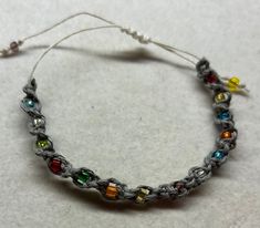 a close up of a bracelet on a white surface with beads and wires attached to it